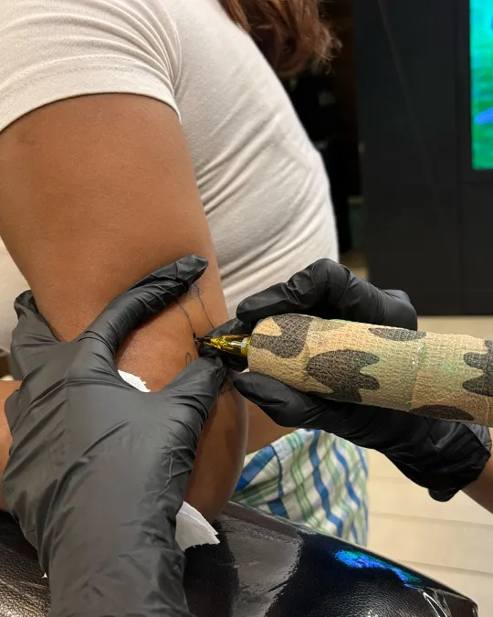 Tattoo artist inking cat design - Aliens Tattoo