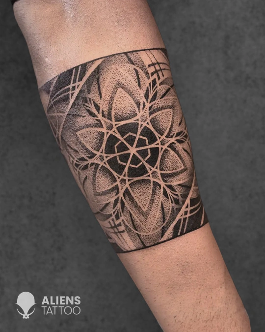 Geometric mandala armband tattoo with dotwork shading in black and grey style