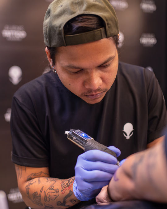 Tattoo artist concentrates while inking a client's arm at best tattoo studio in Kolkata
