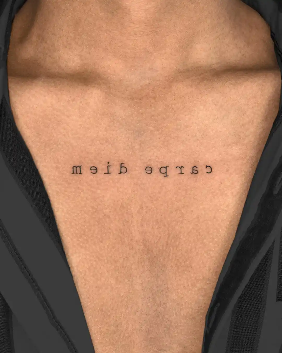 "Carpe Diem" tattoo on a man's chest, written in reverse, encouraging a reminder to seize the day and live in the moment.