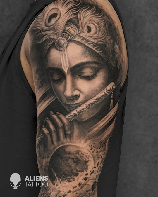 Lord Krishna tattoo playing flute with cosmic background on arm in black and grey realism style