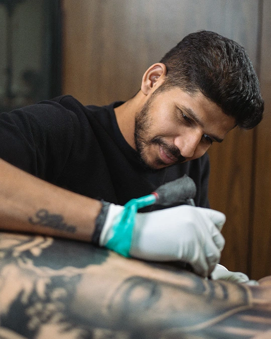 Professional tattoo artist at Aliens Tattoo Malad West carefully tattooing a client with precision and safety