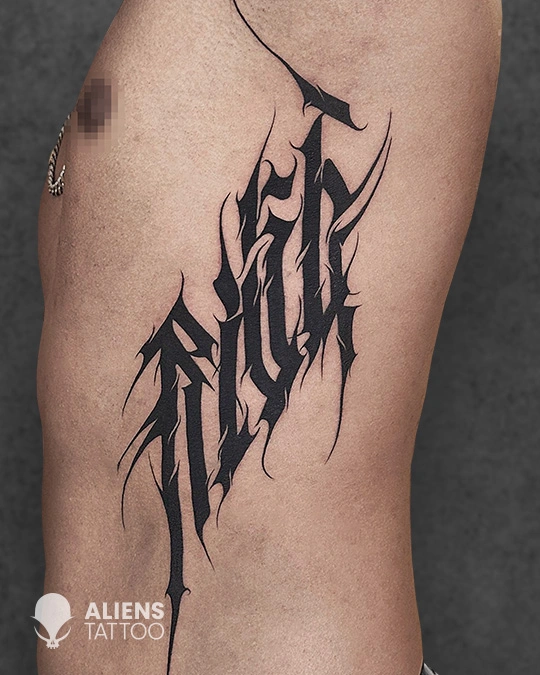Abstract tribal lettering tattoo on rib cage in bold black ink style