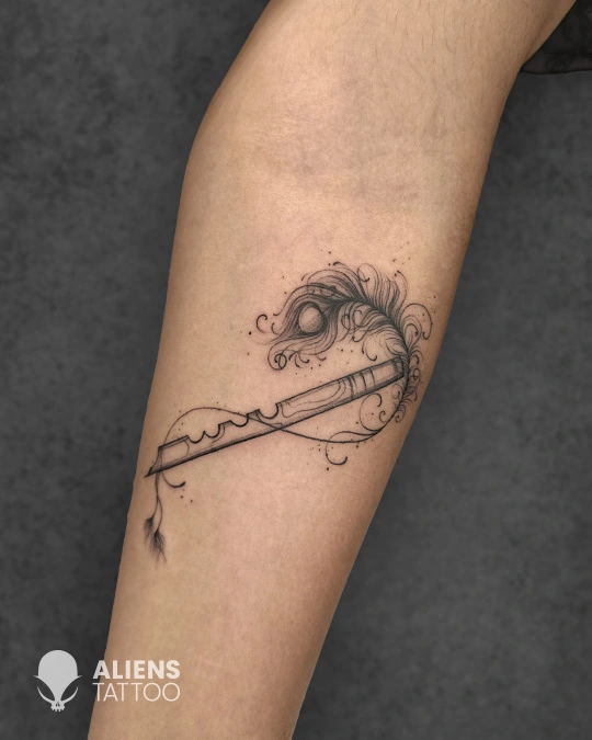 Fine line flute and peacock feather tattoo with ornamental swirl detailing on the forearm, created by Aliens Tattoo, the best tattoo studio in pune.
