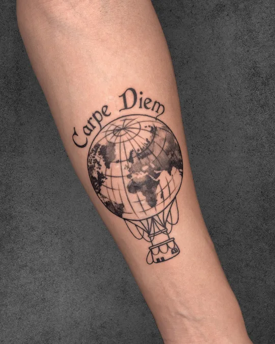 Minimalistic hot air balloon tattoo with "Carpe Diem" on a woman's arm, highlighting a love for travel and seizing the day.