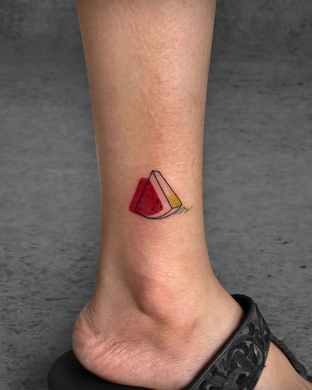 Geometric watermelon tattoo on a woman's ankle, designed in a playful minimalist style, symbolizing freshness and joy.