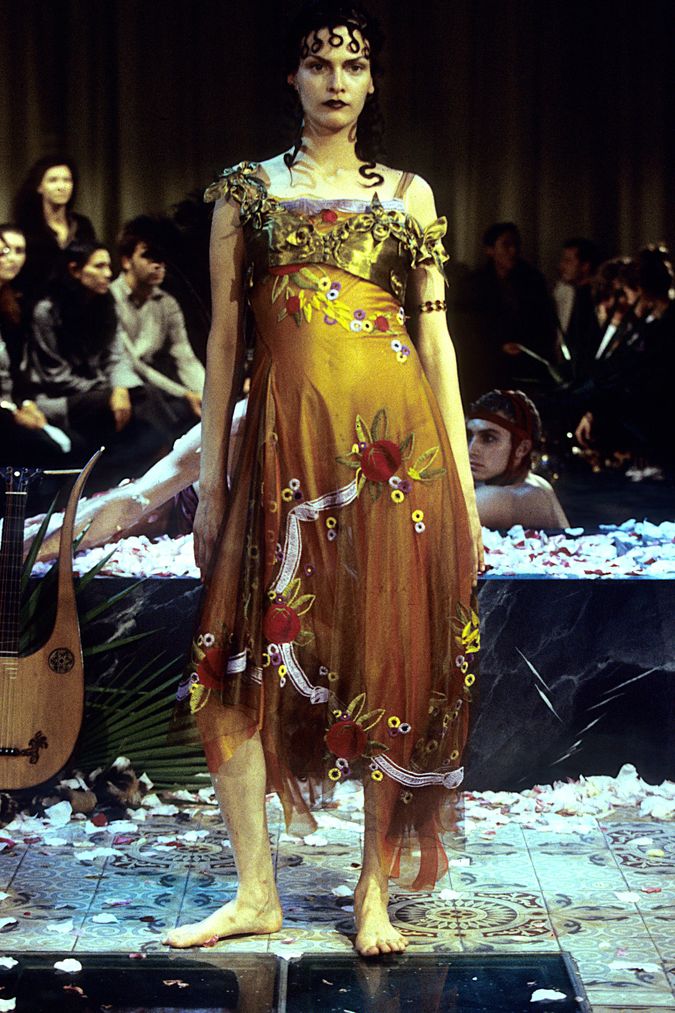 A woman in a golden, floral patterned classical dress
