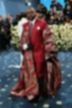 A Black man in a red suit with a red and golden-accent cape.