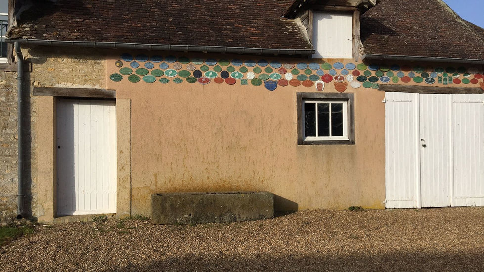 Façade restaurée d'une maison normande avec colombages en bois ancien et soubassement en pierre calcaire.