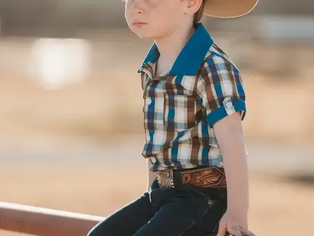 Little cowboy in a plaid western shirt and denim jeans