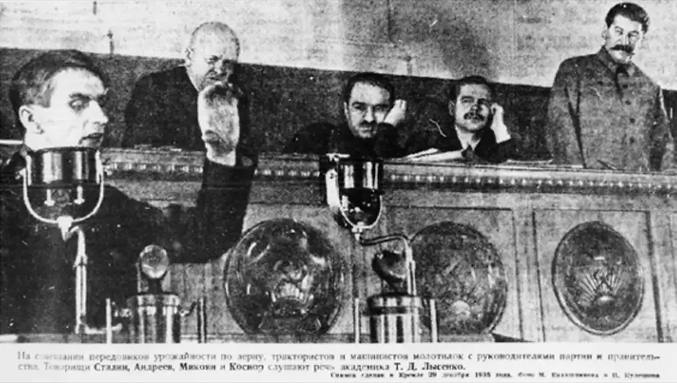 בתמונה משנת 1935, נראה טרופים ליסנקו נושא נאום חוצב להבות, שבו הוא מאשים את הביולוגים מהזרם המרכזי בכך שהם מתנגדים לקולקטיביזם, סותרים את המרקסיזם ופועלים נגד ברה"מ. בקצה הימני של התמונה, סטלין צופה בו בריכוז, ונראה כי הוא מתרשם עמוקות מדבריו.