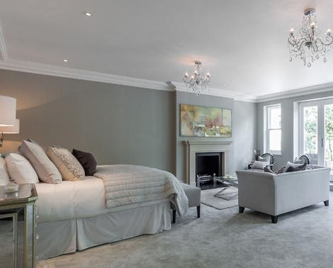Modern grey bedroom with fireplace and seating area.