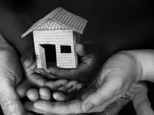 cardboard home held in the hands of a family.