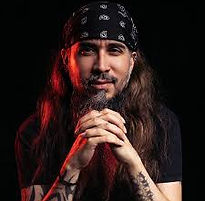 Dr. Mike Mena with long hair, beard, tattoos, and bandana with interlaced fingers