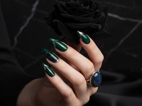 Main avec un nail art dark feminine qui tient une rose noire