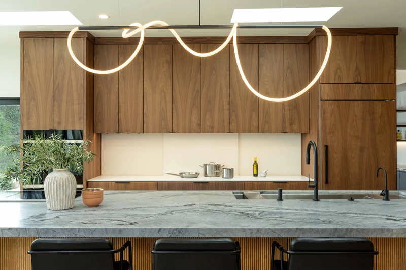Wide view of the island sink, looping pendant light and closed backsplash panels.