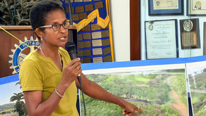 Alice "Nailah" Charles pointing at photo of dark, acidic runoff known as vinasse flowing from the Prosperity Farm