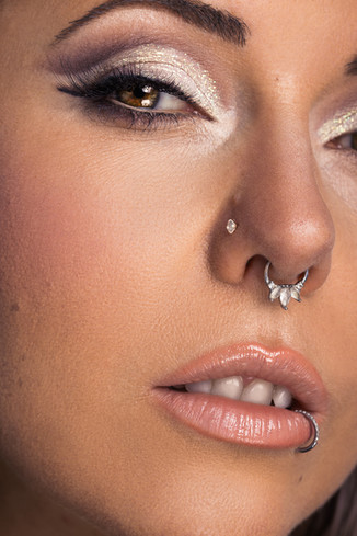 Ein nahes Portrait Bild von einer Frau . Ihr Make-up besteht aus einem weißen glitzer Lidschatten und einem hellen beige farbenden Lippenstift.