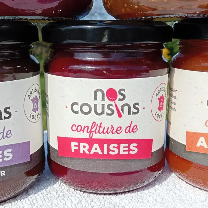 Miniatura: Pot de confiture de fraises de la conserverie Nos Cousins en extérieur sur fond printanier