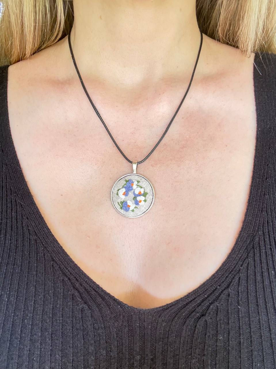 Hand embroidered blue and white bouquet pendant on natural linen in a vintage style round frame. worn
