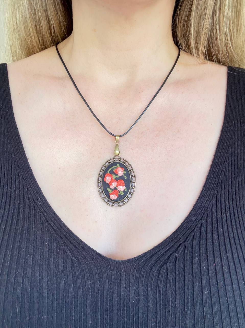 Hand embroidered coral rose pendant in a vintage style oval frame with black waxed cord necklace worn