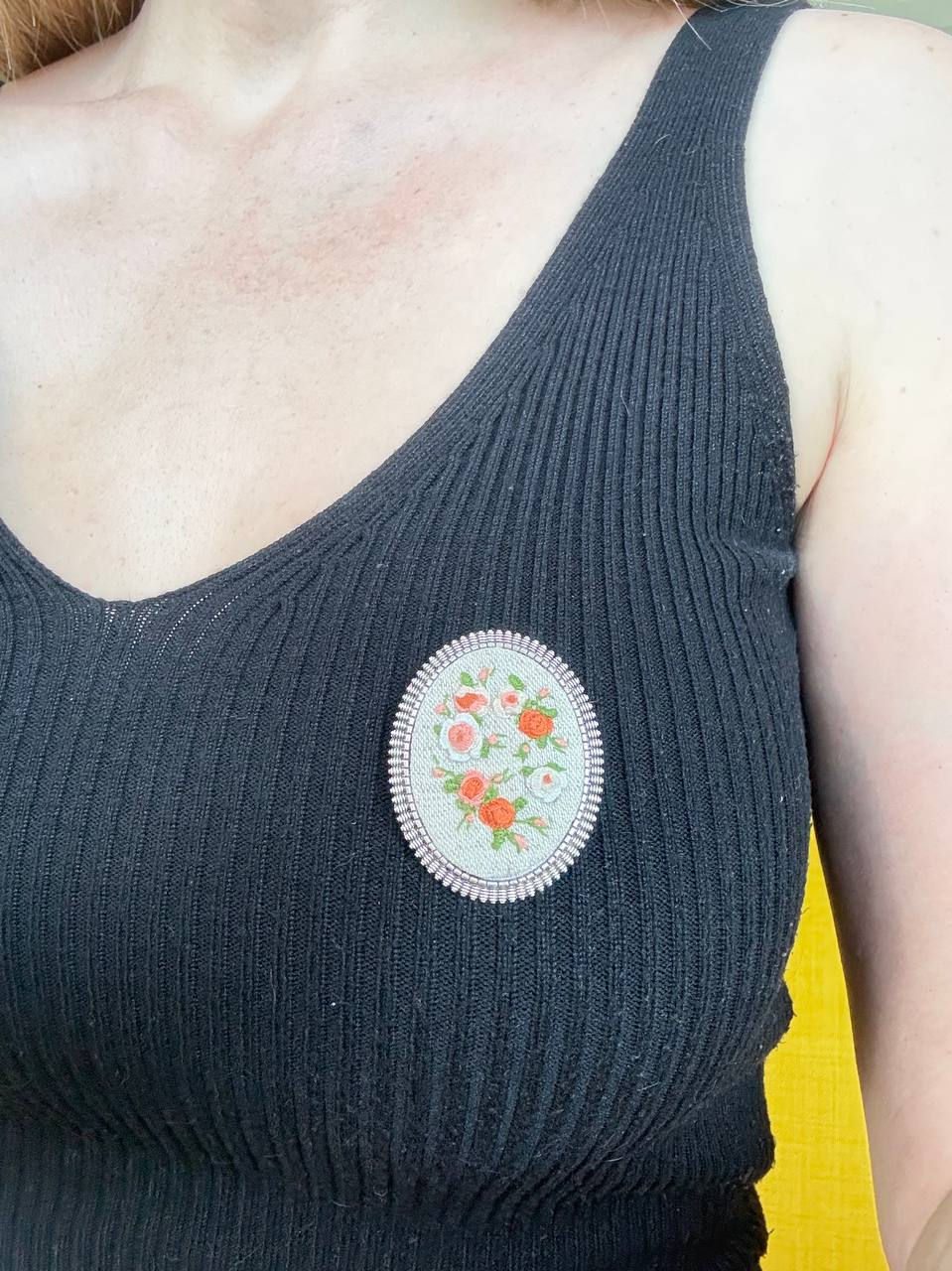 Hand embroidered coral and white floral brooch on natural linen in a vintage style oval frame worn