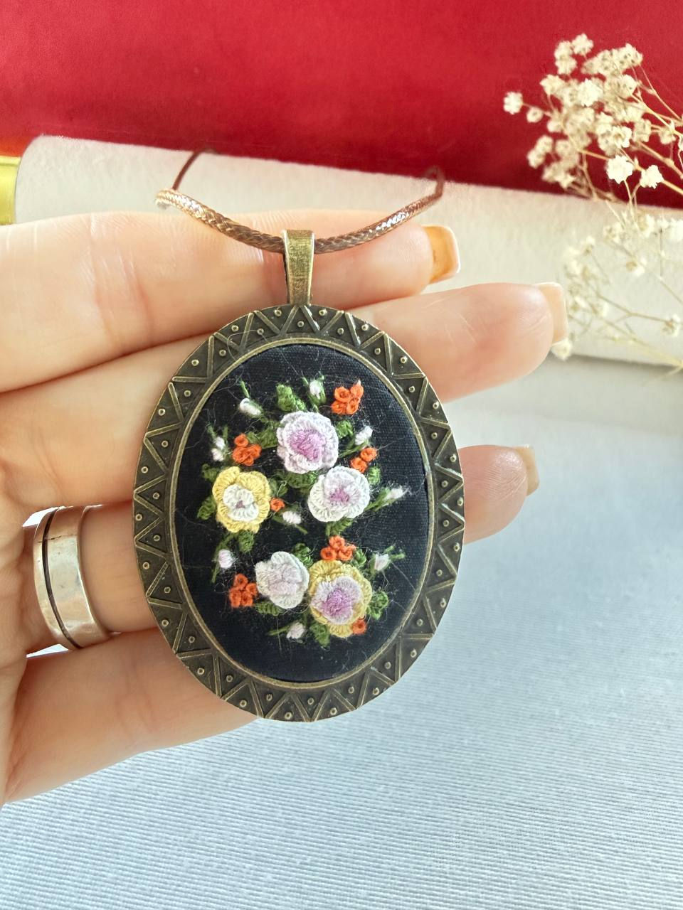 Hand embroidered multicolor floral pendant on black linen in a vintage style oval frame in a hand