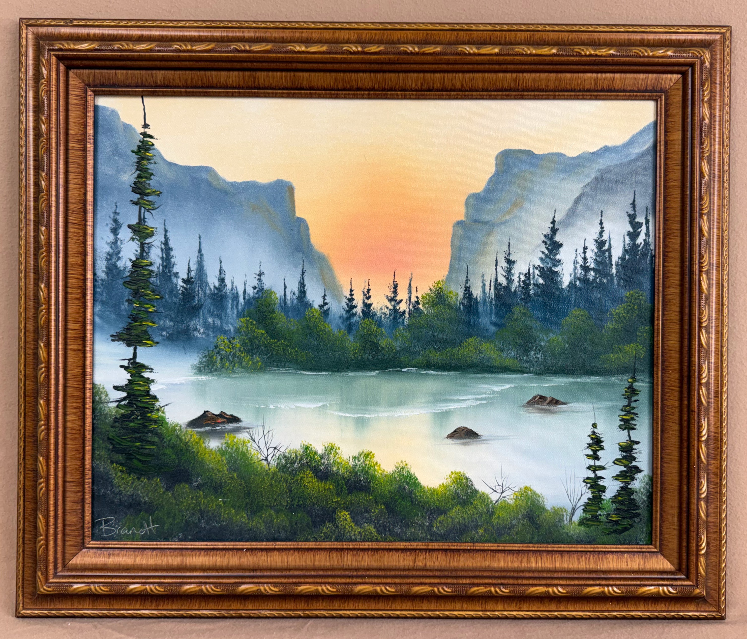 Framed original mountain lake oil painting by Desiree Brandt with evergreens, mist and a peach-orange sunset