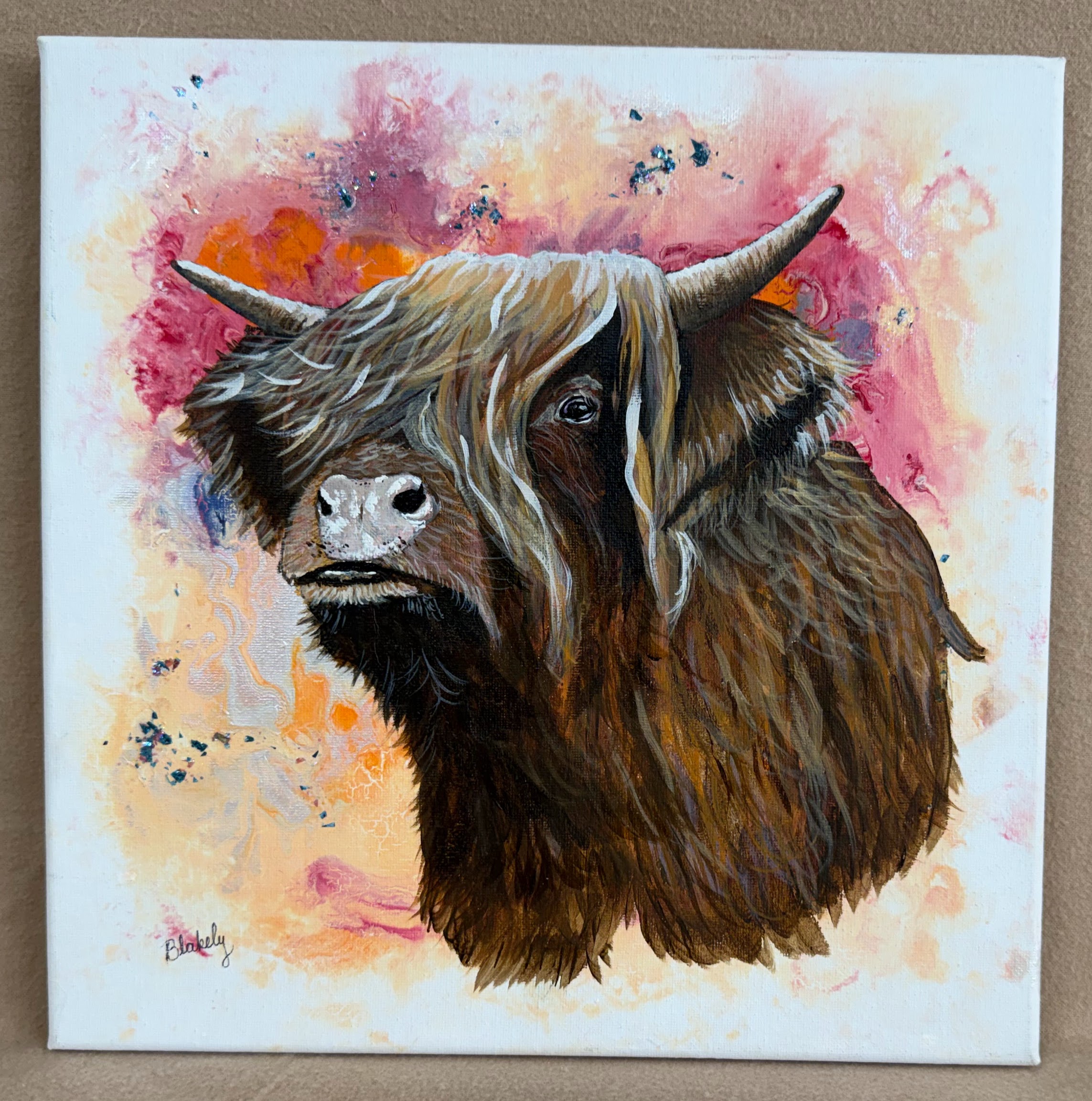 Highland Coo by Hope Blakely, 12 by 12 watercolor and acrylic painting of a shaggy brown Highland cow against pink and orange abstract colors.