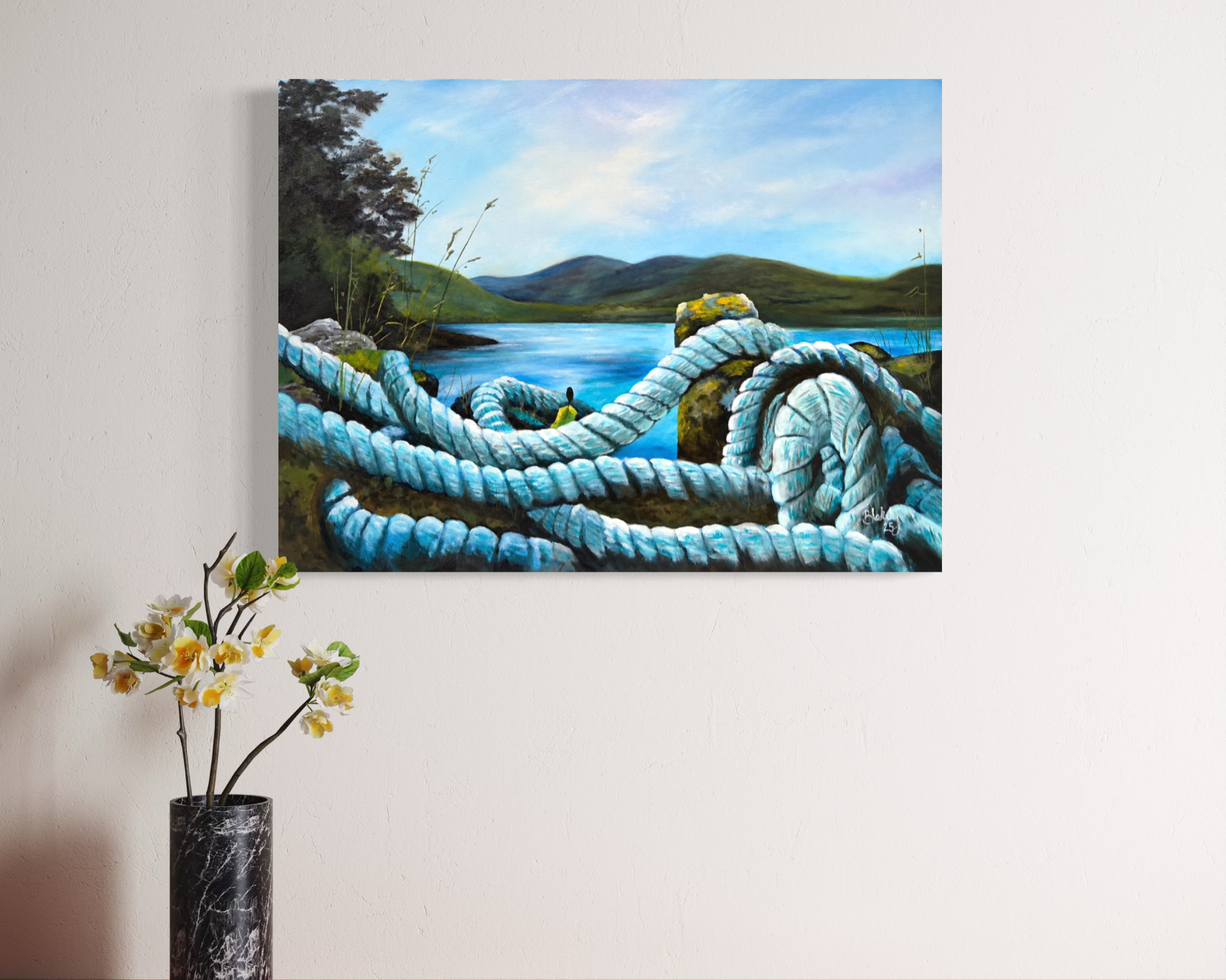Heart Tethered by the Tide seascape hanging over a vase of yellow flowers.