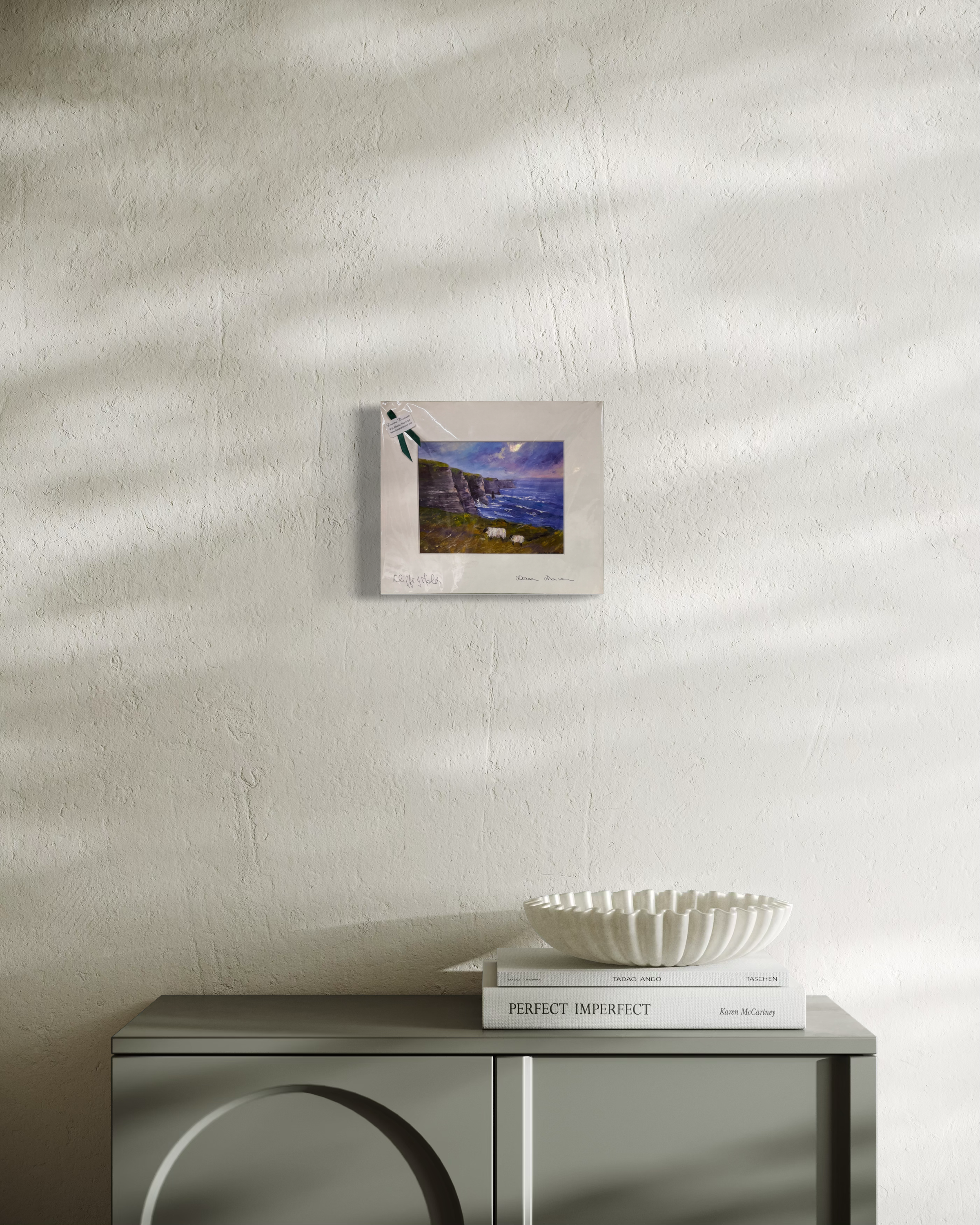 Cliffs of Moher painting displayed over a console in a softly lit room, showcasing its small matted size.