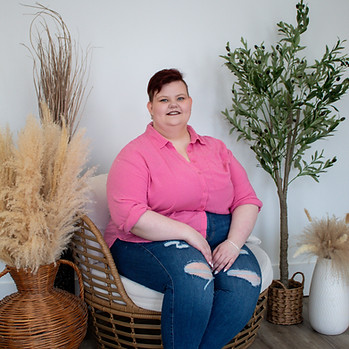 Ashley duDomaine, woman with red hair sitting in front of natural background