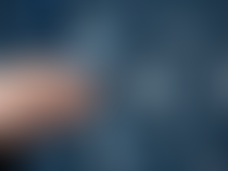 Hand holding magnifying glass over icons of people, symbolizing analysis or recruitment. Blurred blue background with more icons.