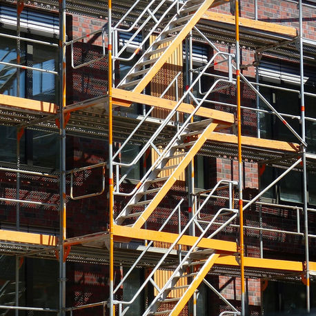 Multi-level scaffolding system with stair access, guardrails and working platforms installed on a commercial building construction project.