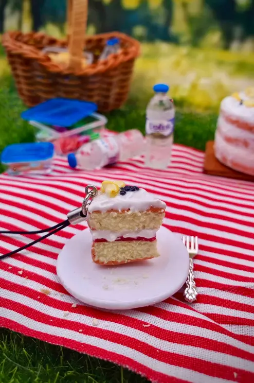 Clay phone charm - slice of sponge cake in picnic scene. 