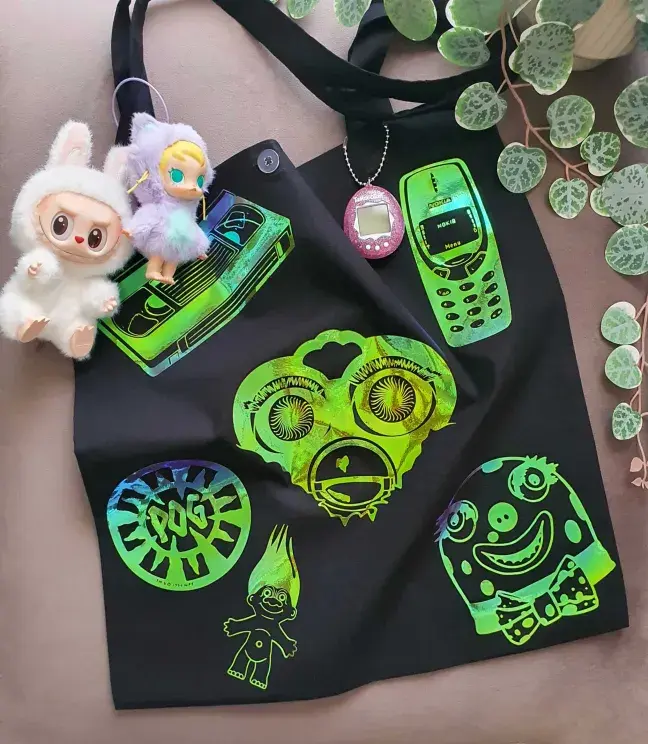 Thumbnail: Black tote bag with retro 80s-90s vinyl designs, displayed with bag charms.