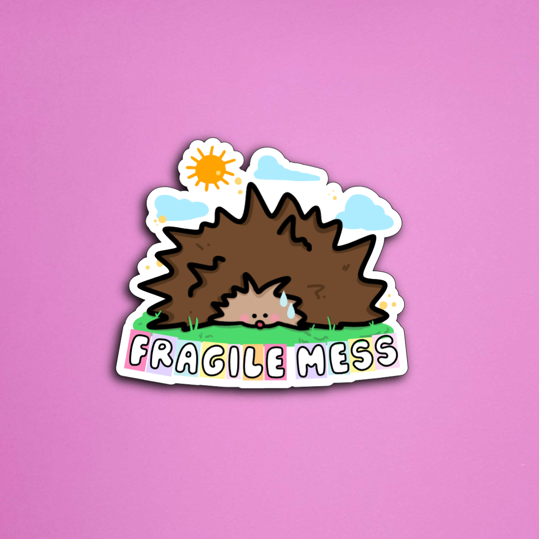 Sticker: Reads "Fragile Mess", cartoon hedgehog with sun and grass.