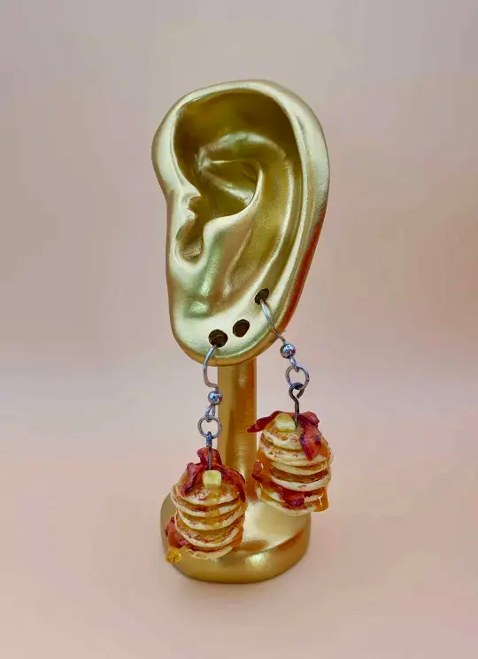 Thumbnail: Golden ear-shaped jewellery display with dangle clay pancake stack earrings.