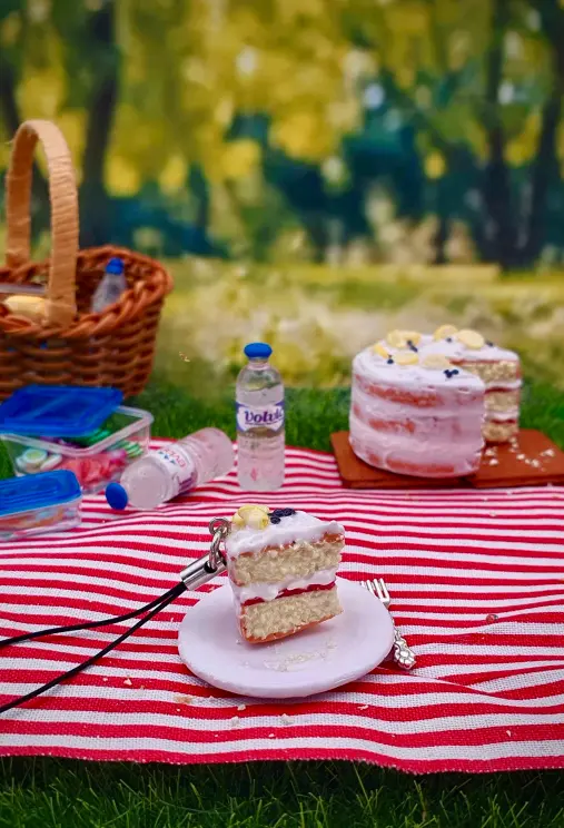 Clay phone charm - slice of sponge cake in picnic scene. 