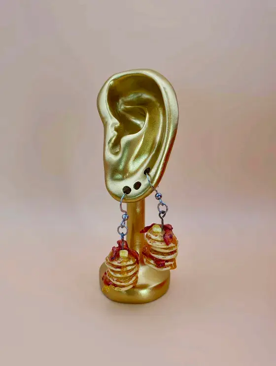 Thumbnail: Golden ear-shaped jewellery display with dangle clay pancake stack earrings.