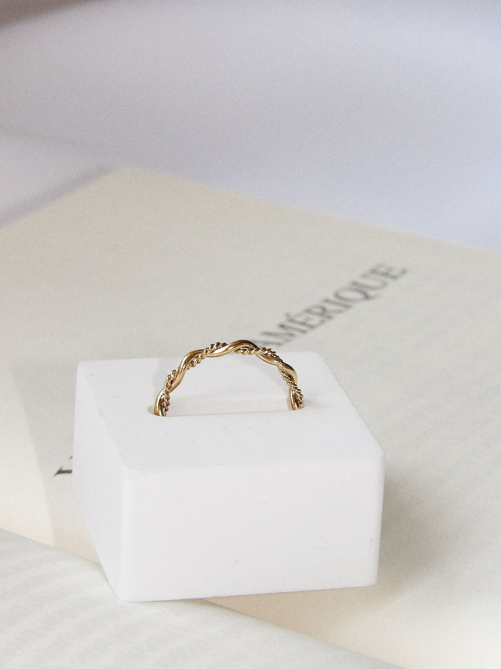 Bague Jenna dorée sur un bloc blanc, texte visible, Macaconcept.