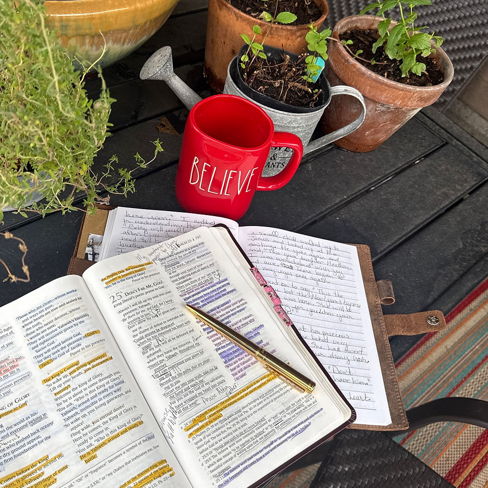 Bible with gold pen and Believe coffee cup on patio with herbs.