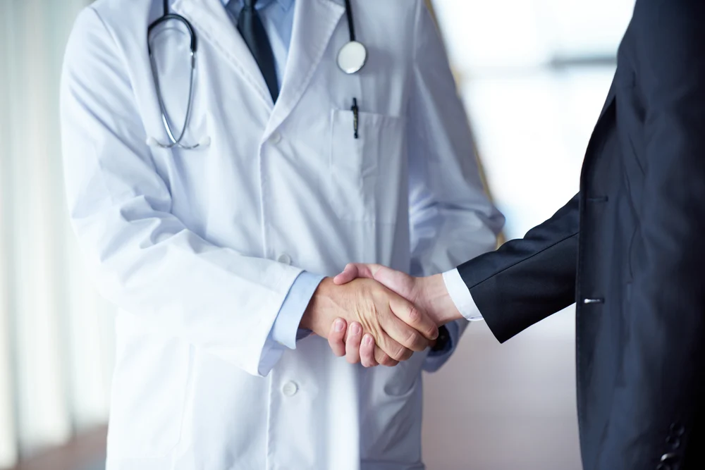 doctor handshake with a patient at doctors bright modern office in hospital.webp