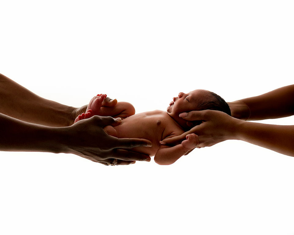 Colour silhouette image of baby being held by mum and dad