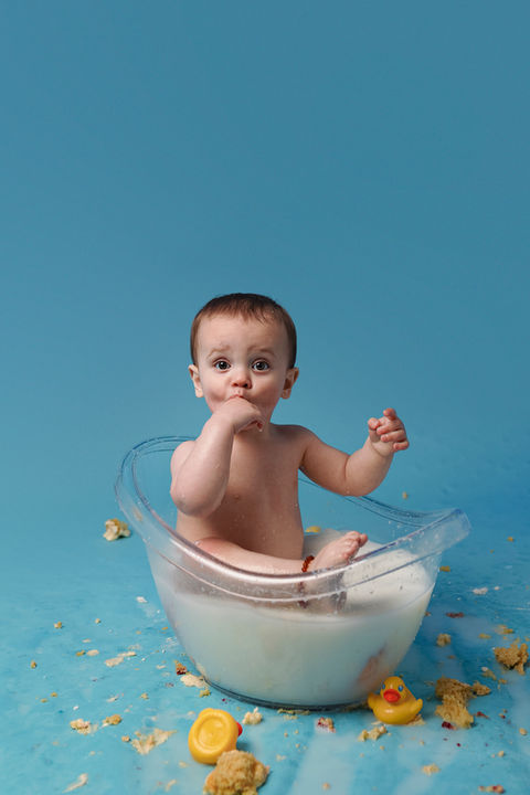 Baby boy pictured in a bath against a blue backdrop