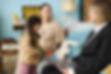Parent and child interacting with professional advisor in home setting with toys and decor