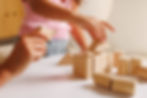 Parent helps preschooler build shapes with wooden blocks, showing play-based learning, fin