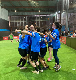 Equipe mixte de football qui fête sa victoire. Les joueurs et joueuses ont l'air très heureux et sautent pour célébrer leur victoire au tournoi de football mixte interentreprise.