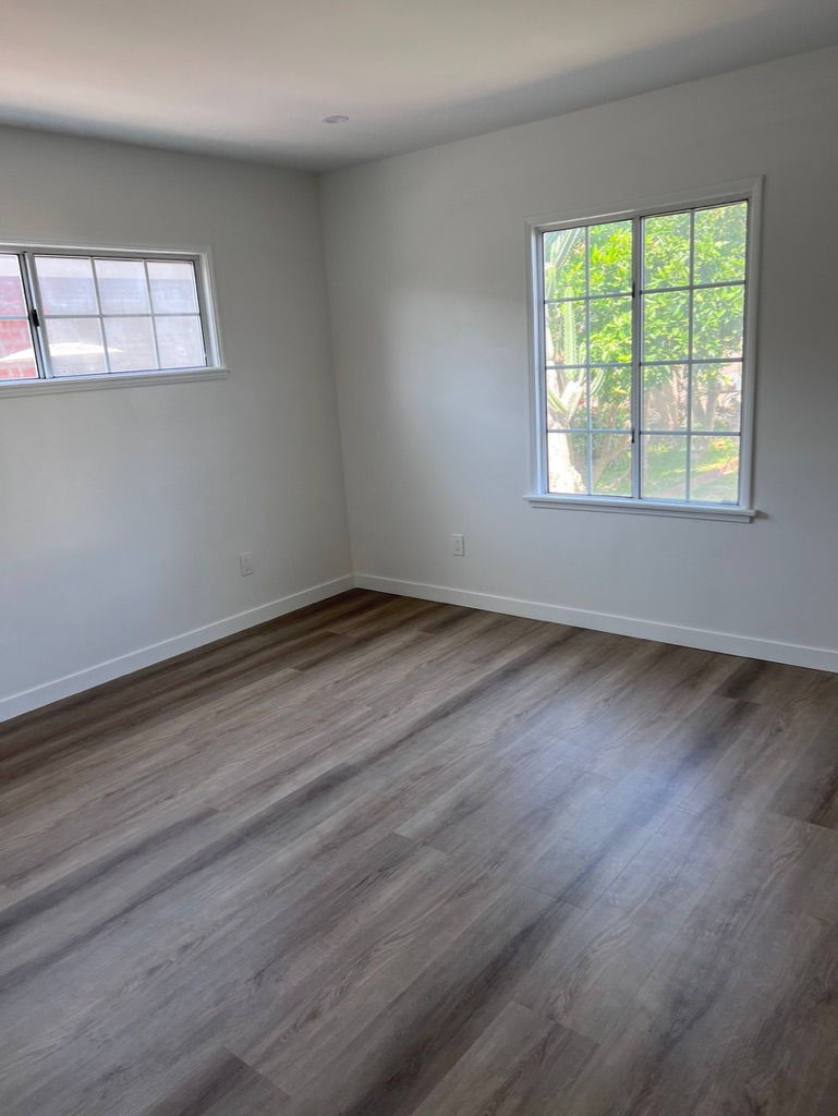an empty room with hardwood floors and a window