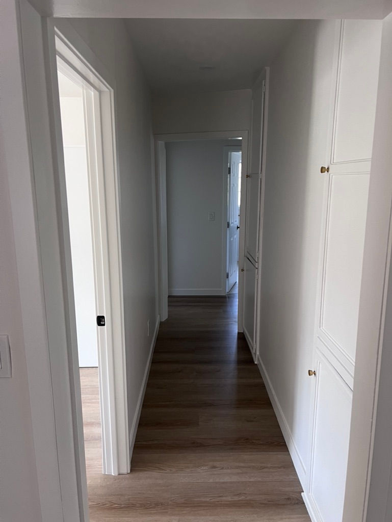 a hallway in a house with white cabinets and hardwood floors